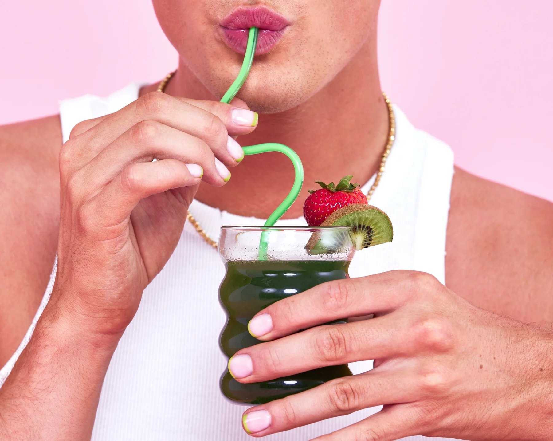 Close crop of hands holding a small glass of greens.