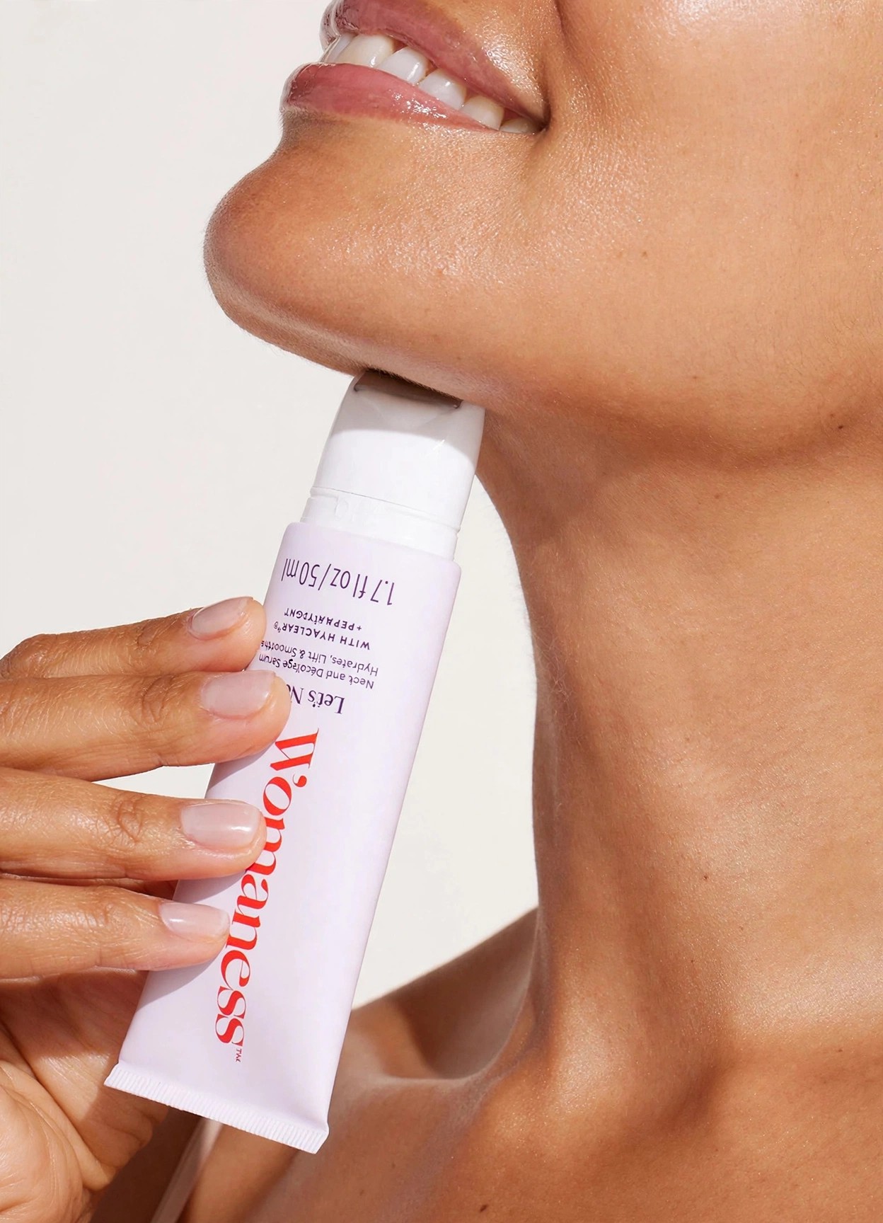 Hand holds a Womaness tube against a chin and neck.